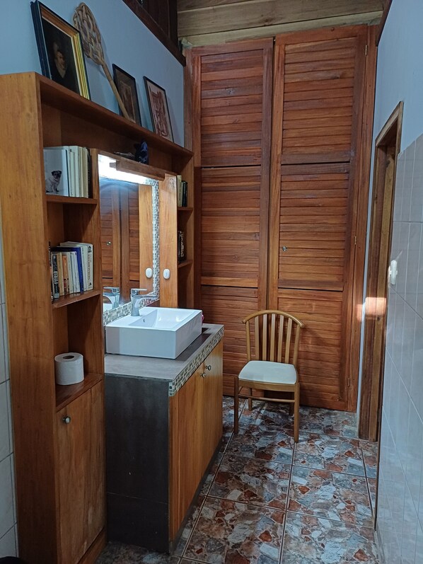A bathroom with a wooden vanity, a sink, and a chair.
