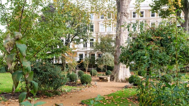 A garden with a pathway leading to a building with white walls and multiple windows. - Lofty Ideals (London)