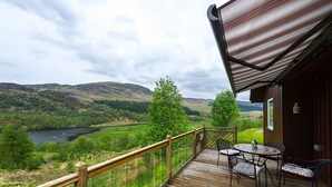 A wooden deck with a view of a river and hills. - Kingfisher Lodge with sensational loch views (Crianlarich)