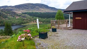 A rustic cabin with a wooden deck and a sign reading "KINGSFISHER." - Kingfisher Lodge with sensational loch views (Crianlarich)