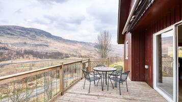 Enjoy outdoor dining on the deck with a scenic view of rolling hills and a river.