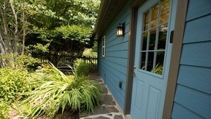 A house with a blue exterior, a front door, and a small garden with various plants.