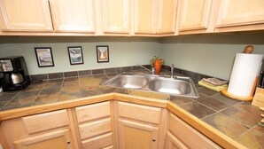 A kitchen with wooden cabinets, a double sink, and a coffee maker.