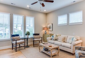 A living room with a sofa, two chairs, a coffee table, and a ceiling fan.