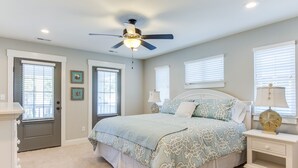 A bedroom with a bed, a ceiling fan, and two bedside tables with lamps.