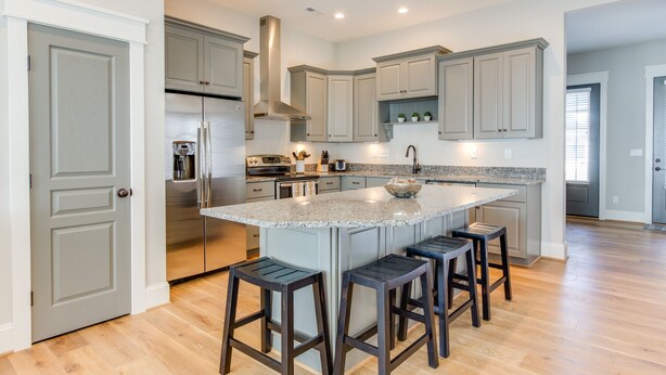 A modern kitchen with a central island, stainless steel appliances, and light gray cabinetry.
