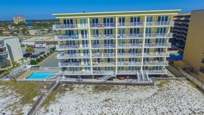 Un hotel de varios pisos con balcones, piscina y vista a la playa.