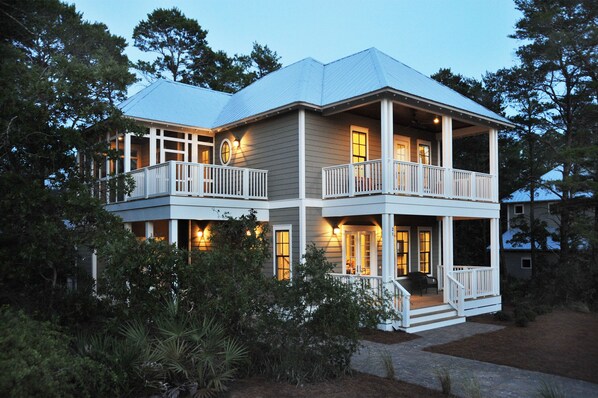 A two-story house with a balcony, a covered porch, and a well-lit entrance.