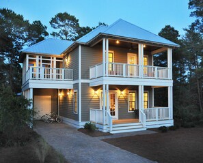 A two-story house with a balcony on the upper level, a covered porch on the lower level, and a bicycle parked outside.