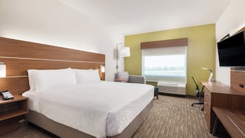 A hotel room with a large bed, bedside tables, a desk with a chair, a flat-screen TV, and a window with a view.