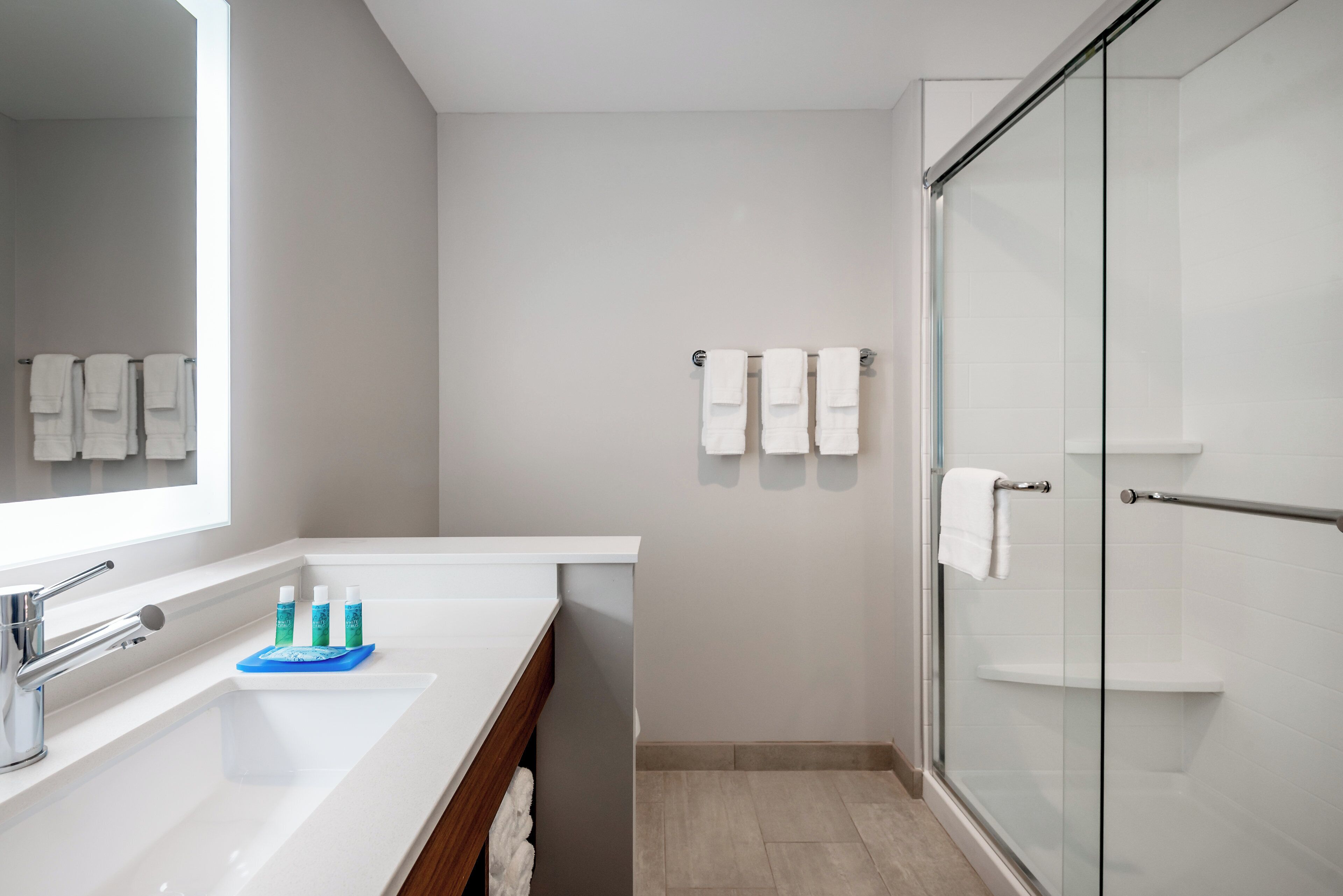 Un baño moderno con un espejo grande, un lavabo y una cabina de ducha de vidrio.