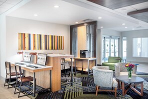 A modern hotel lobby with a reception desk, seating area, and a large abstract painting on the wall. - Holiday Inn Express & Suites Punta Gorda by IHG (Punta Gorda)