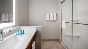 A modern bathroom with a large mirror, a sink, and a glass shower enclosure.