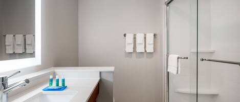 Un baño moderno con un espejo grande, un lavamanos y una cabina de ducha de vidrio.