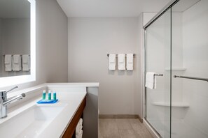 Een moderne badkamer met een grote spiegel, een wastafel en een douchecabine met glazen wanden.