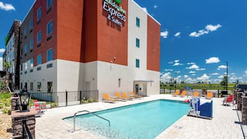 Edificio de Holiday Inn Express con piscina, mobiliario exterior y cielo despejado.