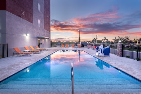 Una piscina al aire libre, sillones reclinables de piscina
