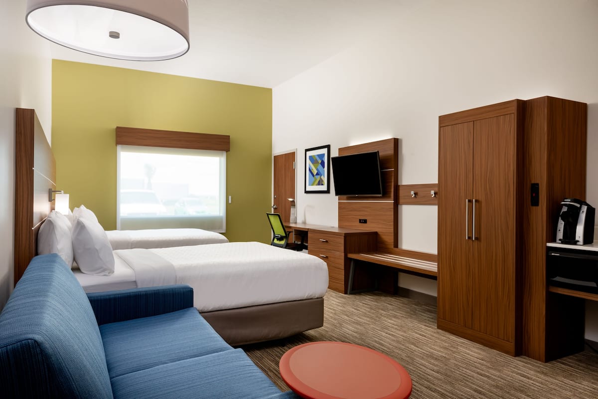 A hotel room with a bed, a sofa, a desk, a television, and a wardrobe.