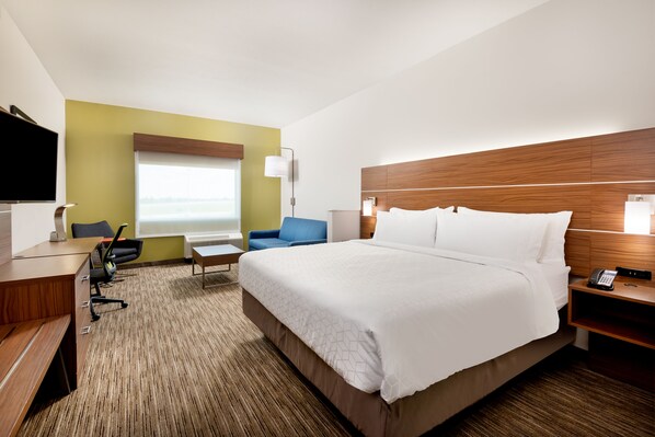 Een hotelkamer met een groot bed, een bureau, een stoel, een televisie en een raam met uitzicht.