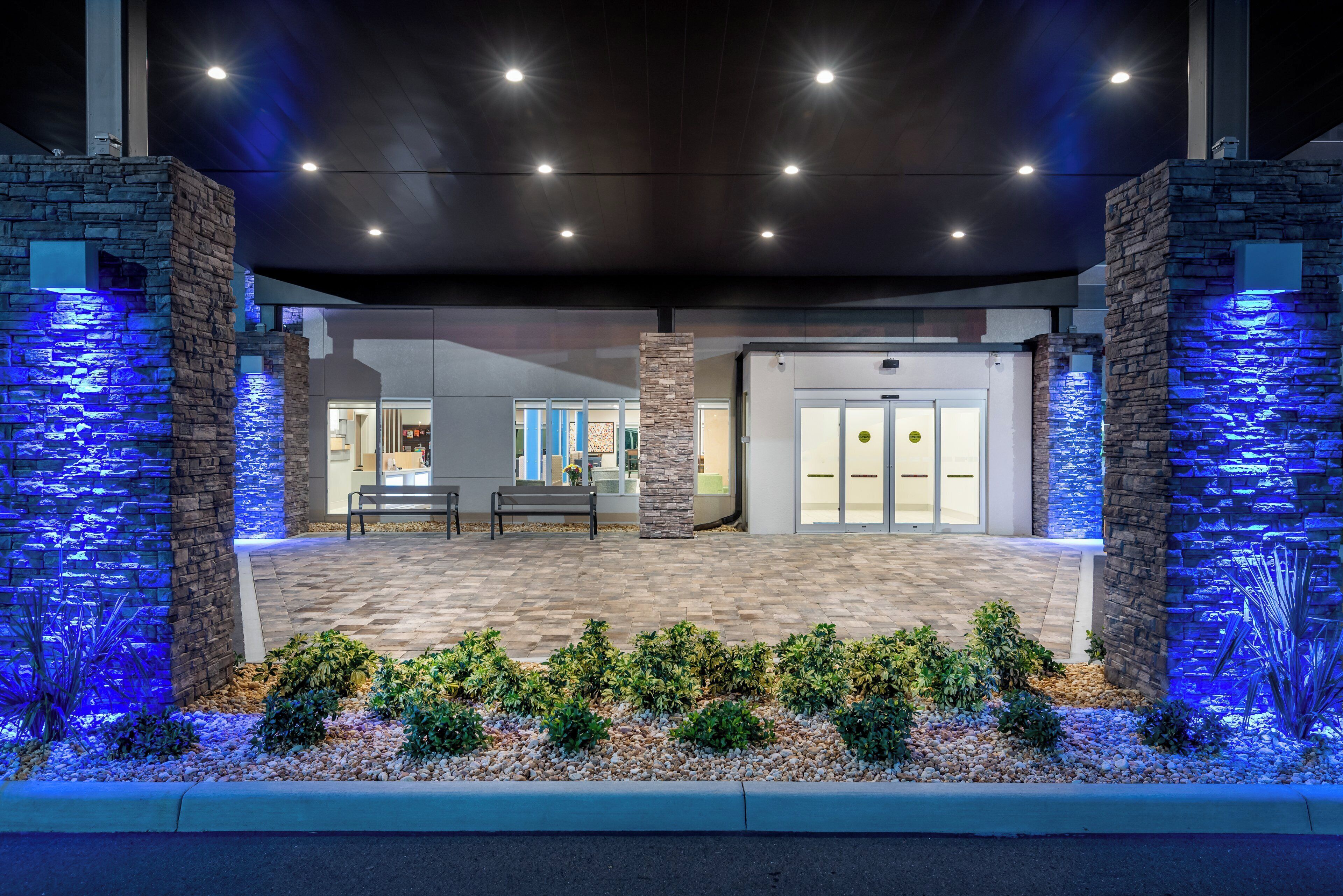 A building entrance with a stone facade, a bench, and a water feature.