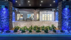 A building entrance with a stone facade, a bench, and a water feature. - Holiday Inn Express & Suites Punta Gorda by IHG (Punta Gorda)