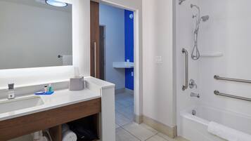 A bathroom with a sink, mirror, and shower.