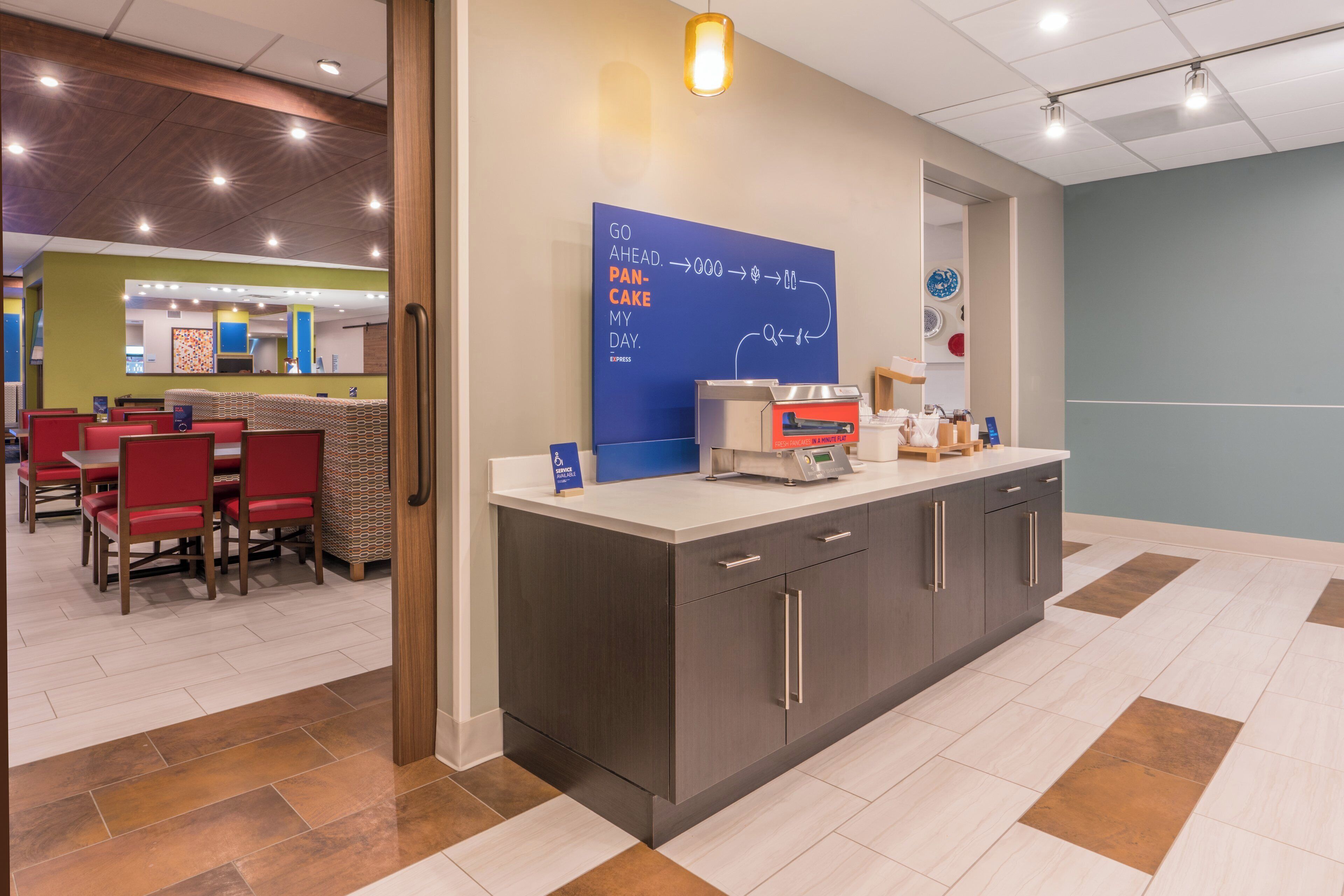 A modern kitchen area with a counter, a coffee machine, and a menu board.