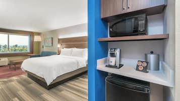 Een hotelkamer met een bed, een bureau met koffiezetapparaat, een magnetron en een afvalbak.