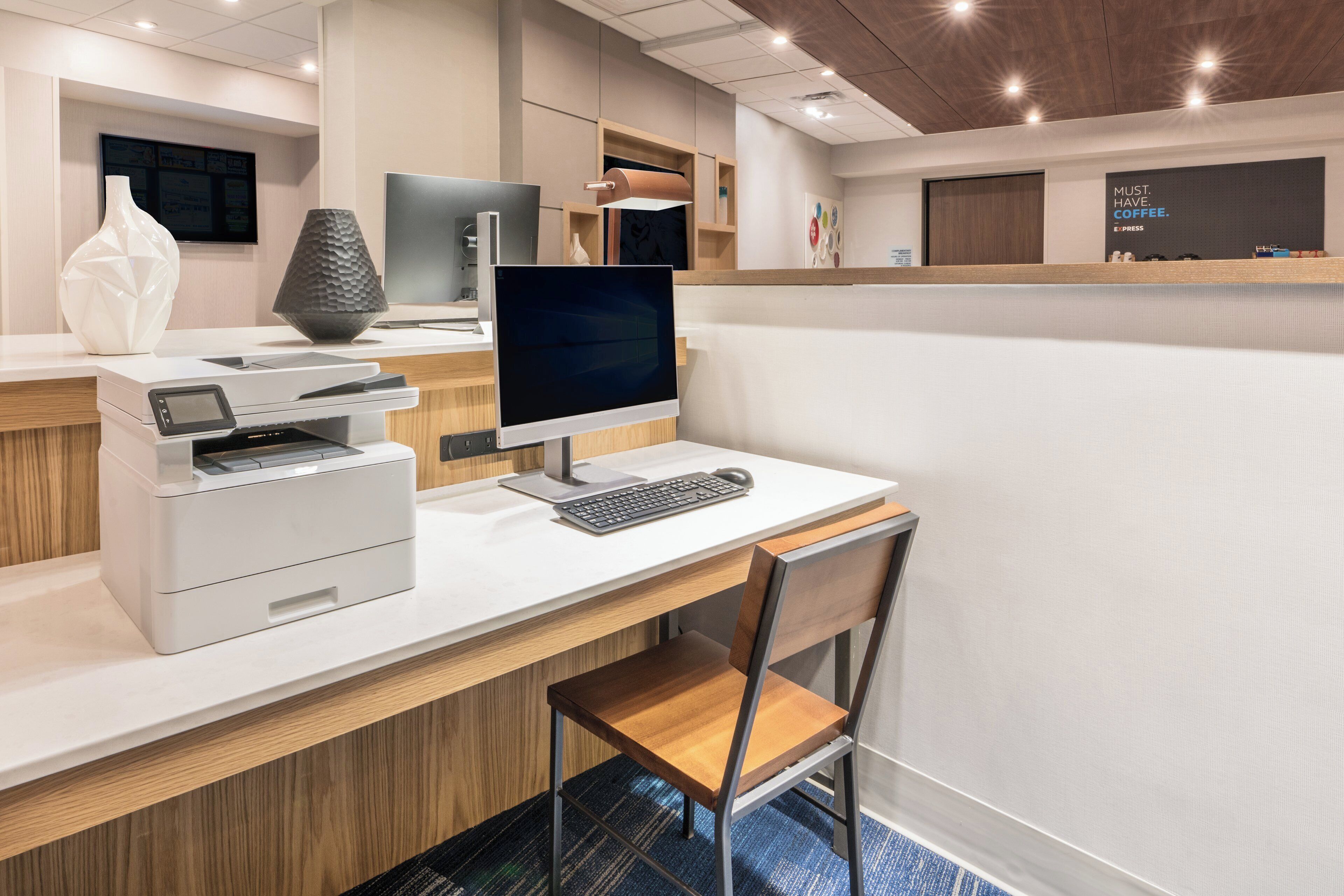 Een moderne kantoorruimte met een bureau, computer, printer en stoel.