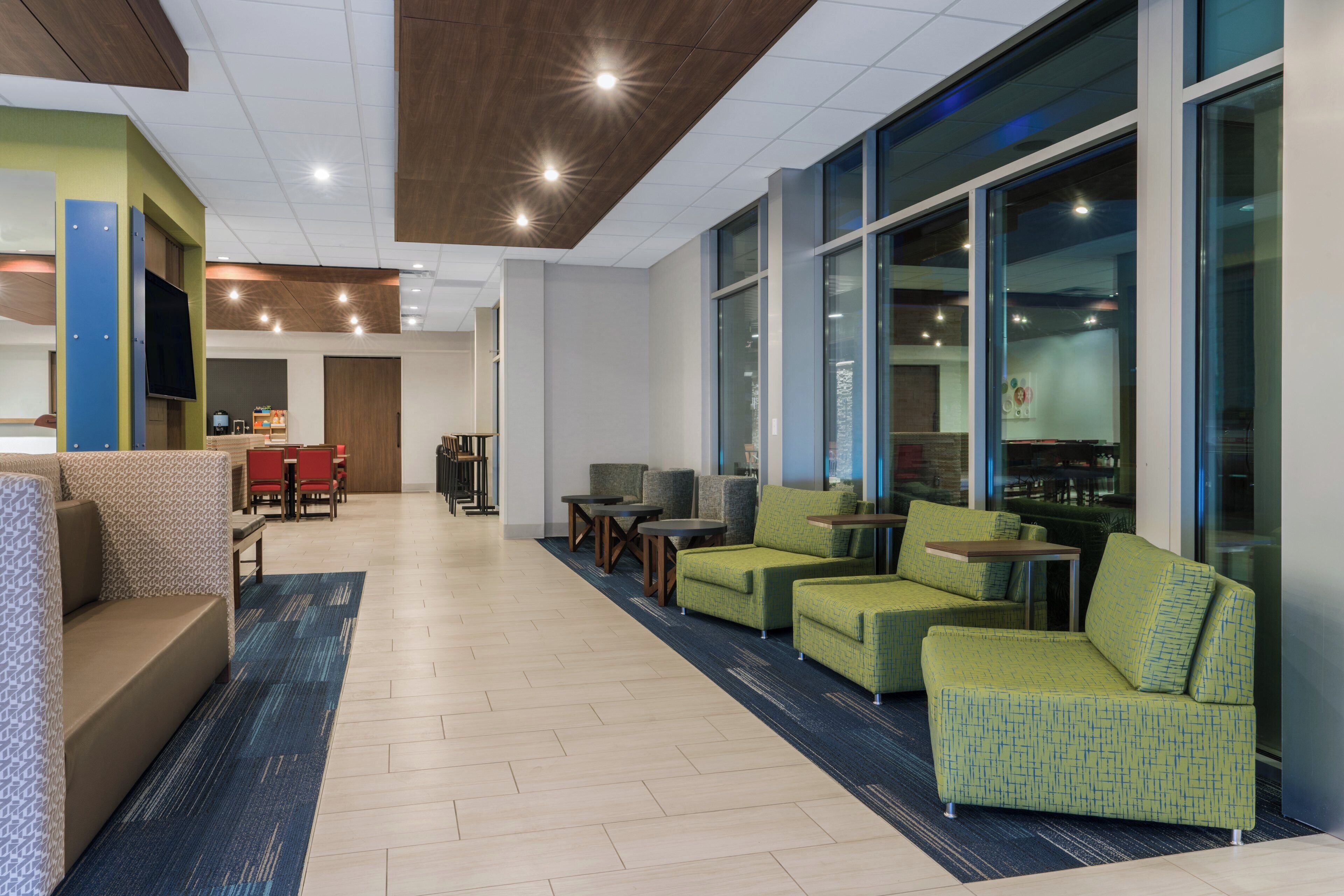 A modern lobby with a seating area, a reception desk, and large windows.