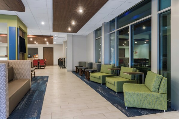 Een moderne lobby met een zithoek, een receptiebalie en grote ramen.