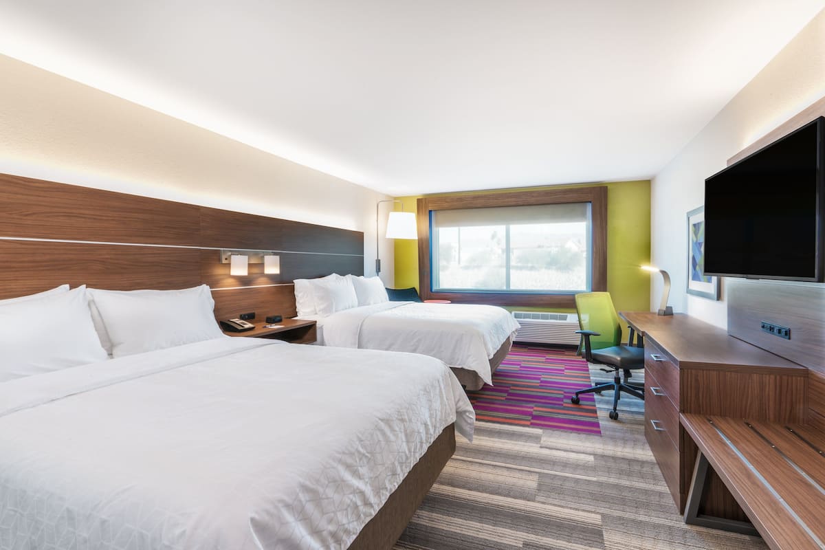 Une chambre d’hôtel avec deux lits, un bureau, une télévision et une grande fenêtre.