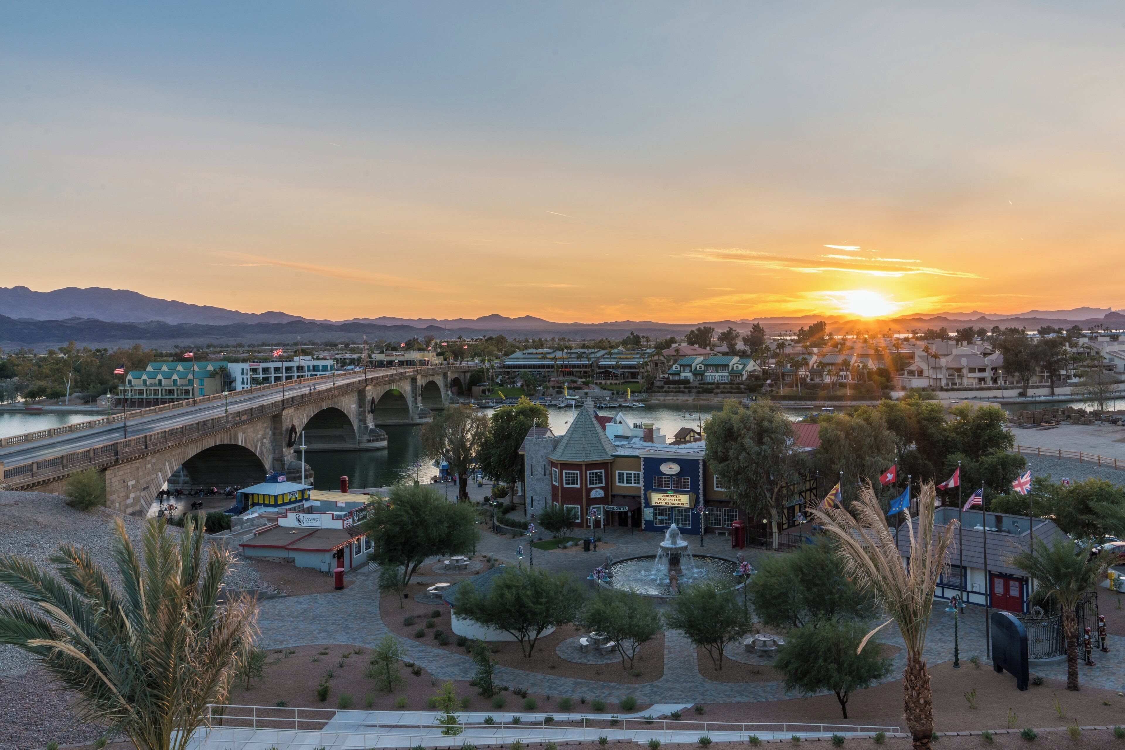 A riverside town with a bridge, buildings, and a fountain.