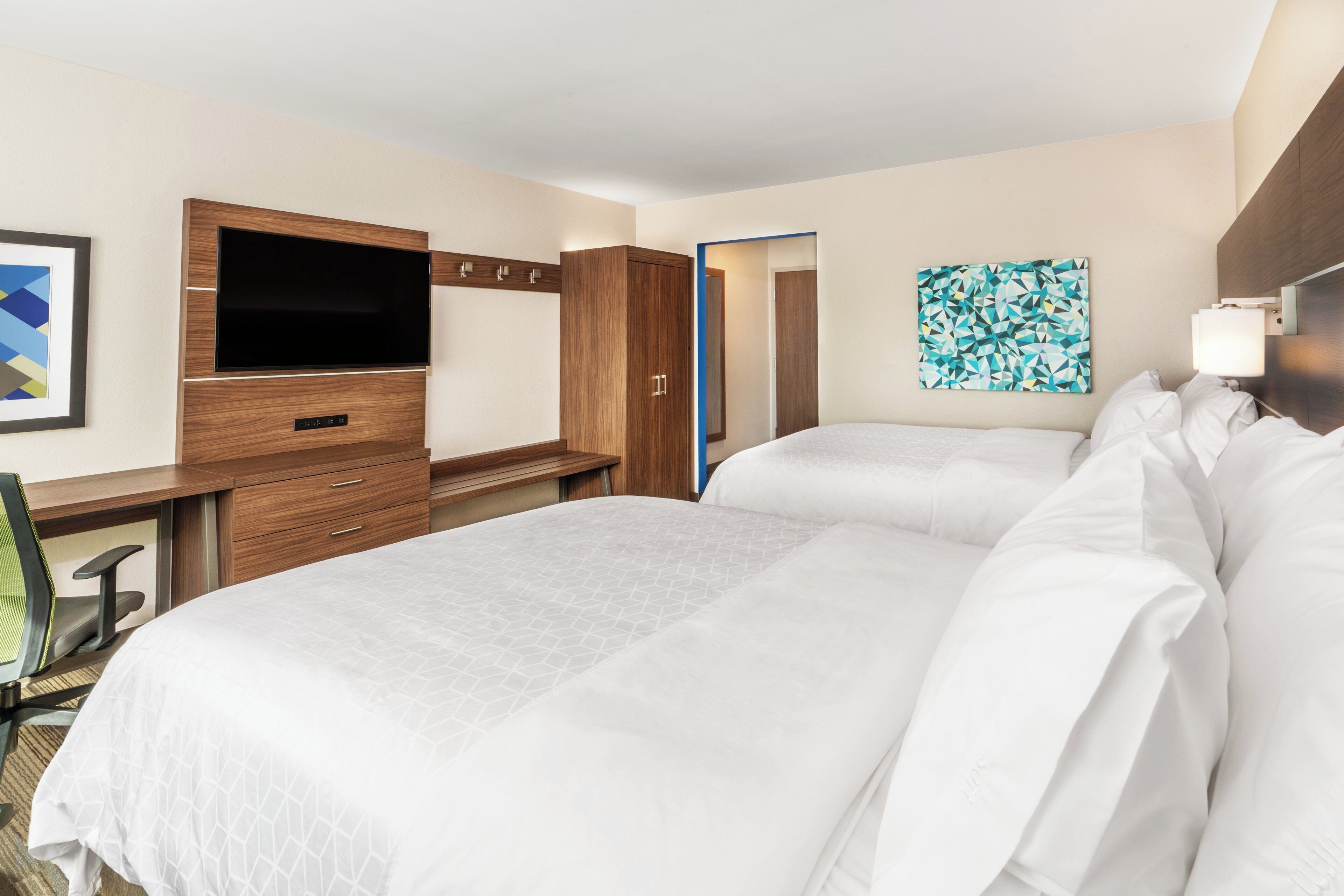 Een hotelkamer met twee bedden, een televisie, een bureau en een spiegel.