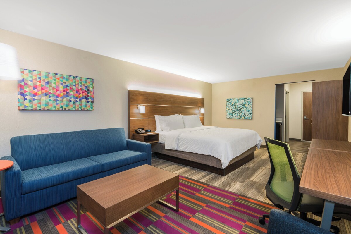 Une chambre d’hôtel avec un lit, un canapé, un bureau et une chaise.