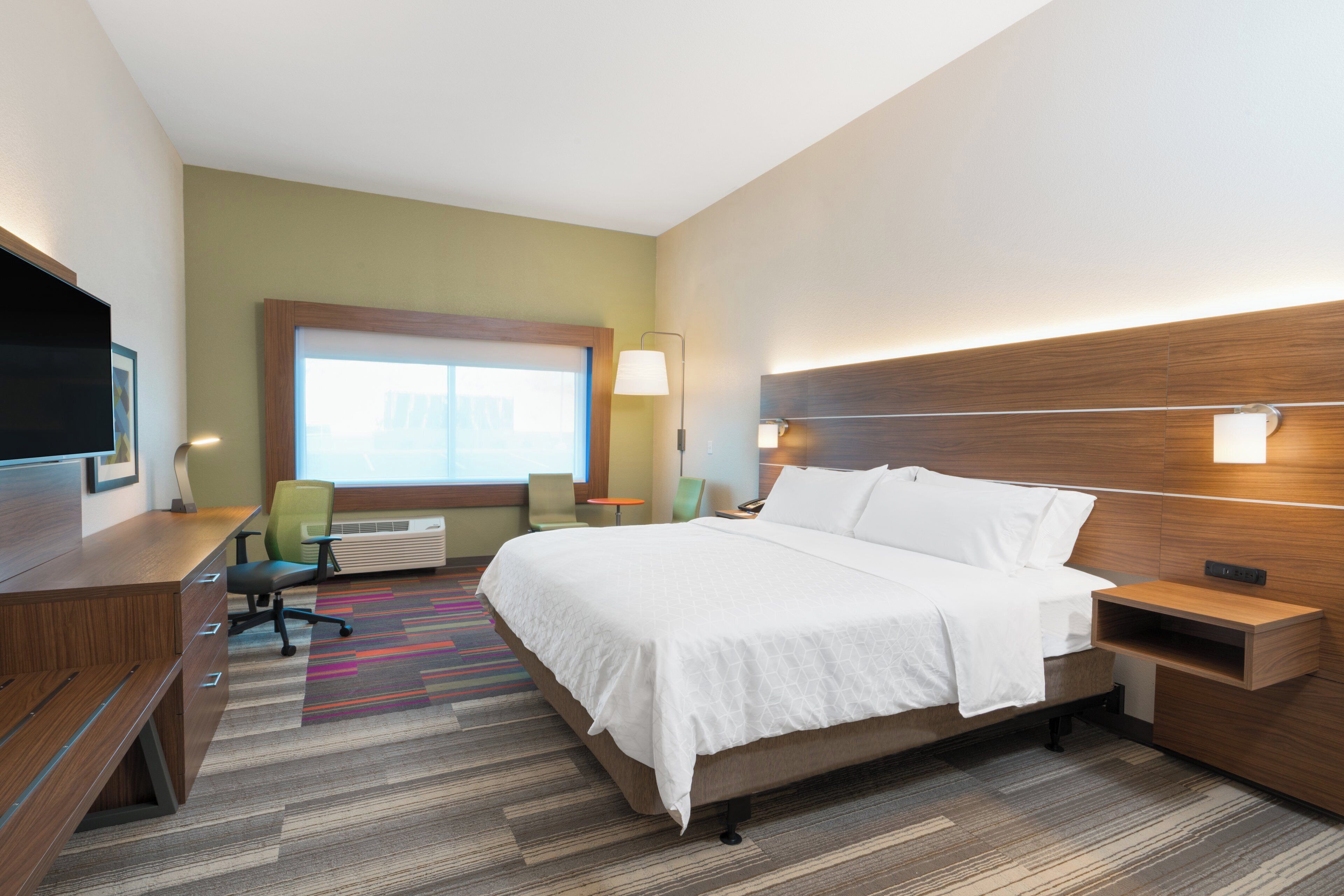 Una habitación de hotel con cama, escritorio, silla y televisor.