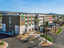 A Holiday Inn Express & Suites hotel with a parking lot, palm trees, and a clear view of the surrounding area.
