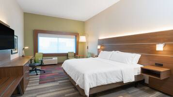 A hotel room with a bed, desk, chair, and a TV.