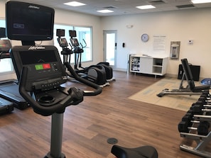 A fitness center with treadmills, elliptical machines, and a weight bench.