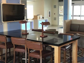 A conference room with a large table, chairs, a projector screen, and a couch.