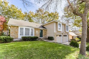 A two-story house with a stone facade, a front porch, and a garage.