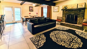 Una sala de estar con un sofá de cuero negro, una chimenea y un comedor con mesa y sillas.
