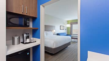 A hotel room with a bed, a microwave, a coffee maker, and a mini-fridge.