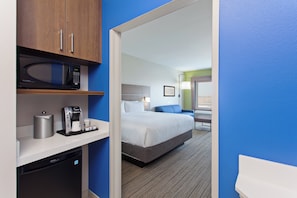 Una habitación de hotel con microondas, cafetera y refrigerador compacto en la encimera.