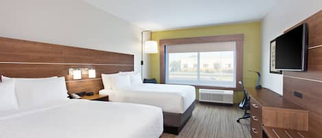 Habitación de hotel con dos camas, televisión, escritorio y ventana con vistas.