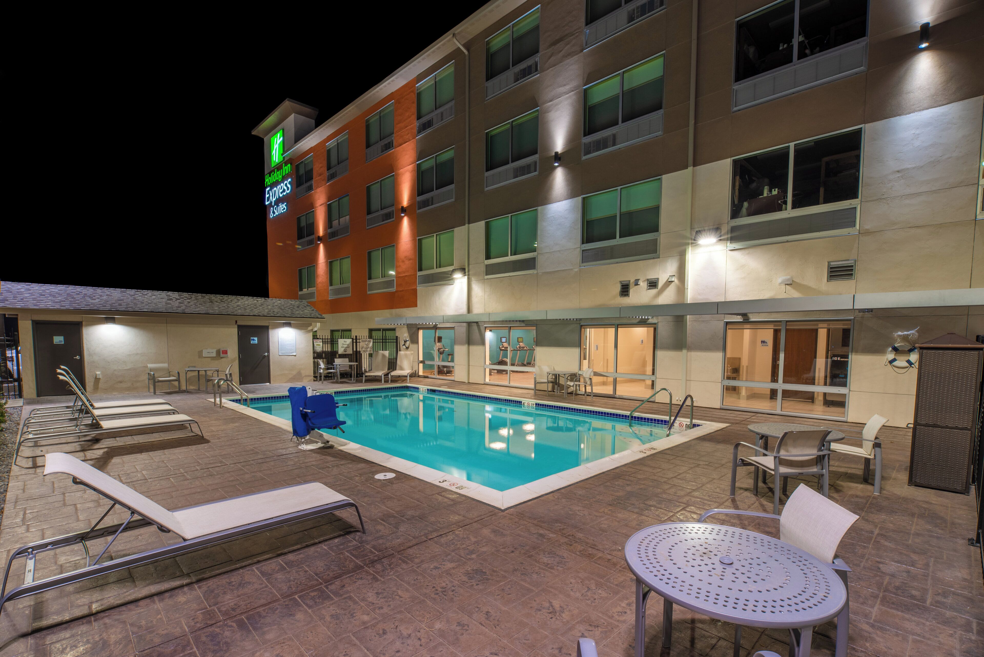 A hotel with a swimming pool, outdoor seating, and a sign for Holiday Inn Express & Suites.