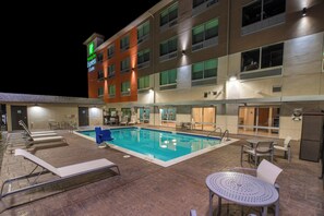A hotel with a swimming pool, outdoor seating, and a sign for Holiday Inn Express & Suites.