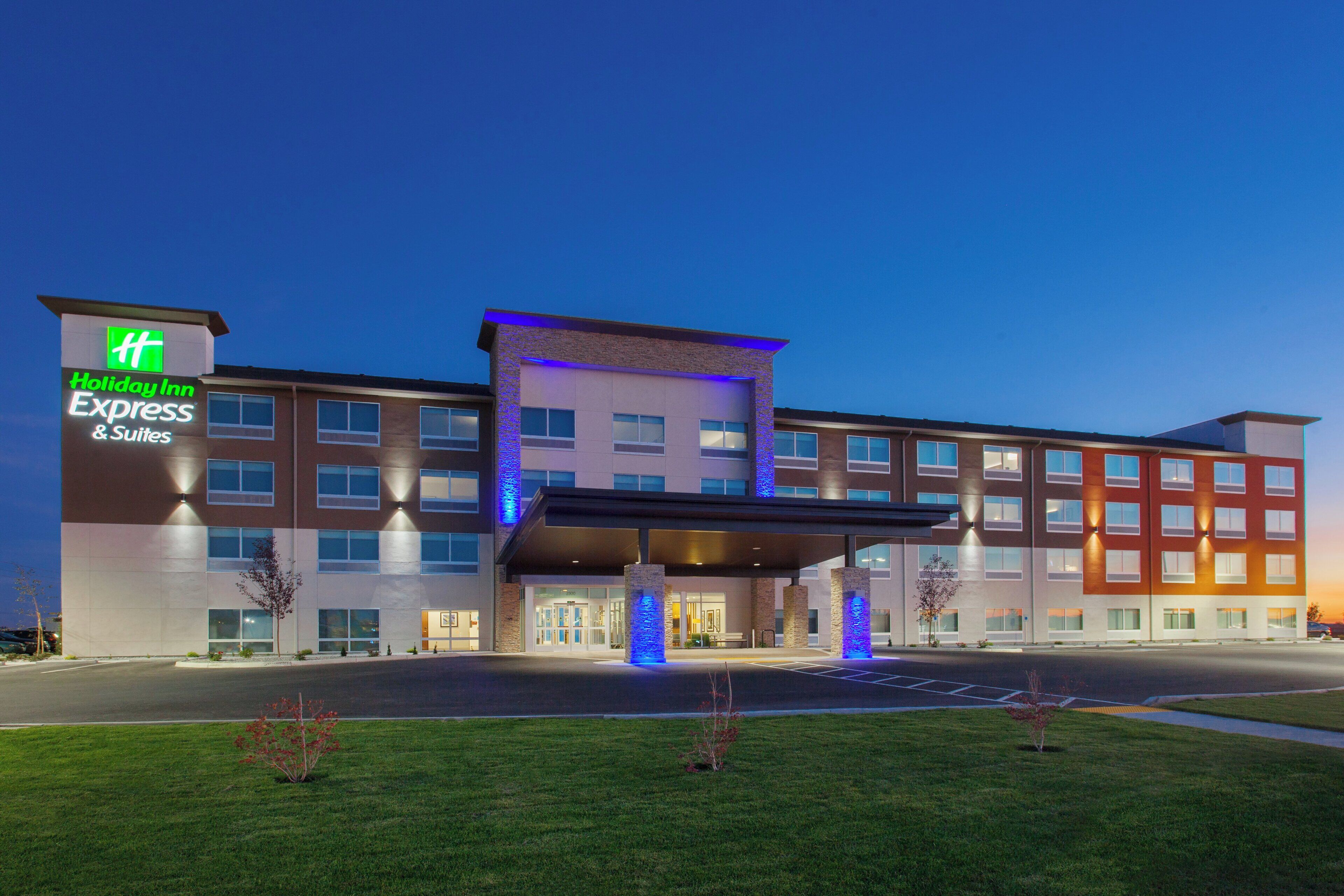 Ein Holiday Inn Express & Suites Hotel mit modernem Design, mit einem markanten Eingang und einer gut beleuchteten Fassade.