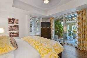 Ein Schlafzimmer mit einem großen Bett, einem Fernseher und einer Glastür, die auf eine Außenpatio führt.