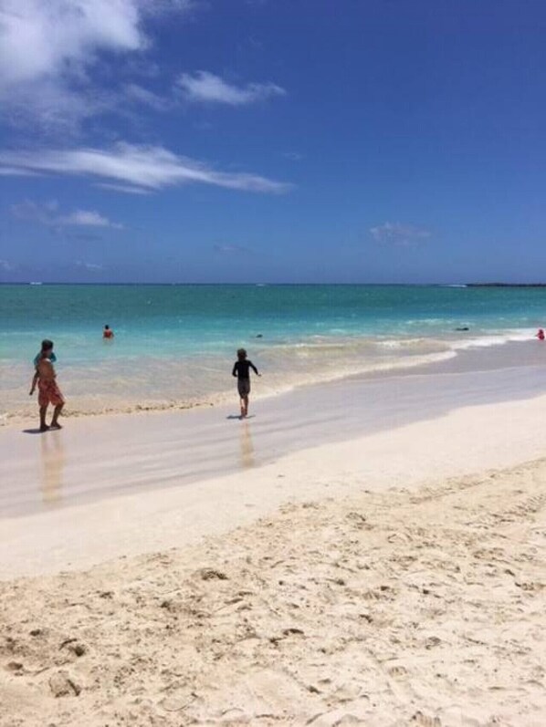 A beach with clear blue water and a sandy shore.